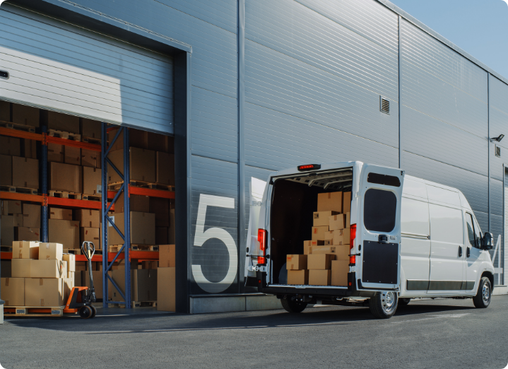 Outside of Logistics Warehouse with Open Door, Delivery Van Loaded with Cardboard Boxes. Truck Delivering Online Orders, Purchases, E-Commerce Goods, Wholesale Merchandise.